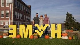 一个家庭站在校园里的H-O-M-E字母周围